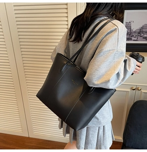 Detailed view of the Fashion Trend Studio black leather tote bag on a shoulder