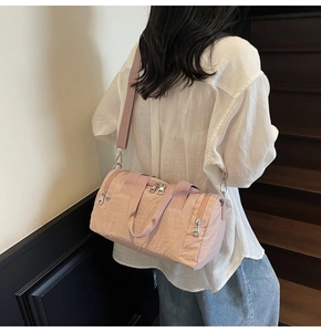Detail view of pink nylon travel bag with multi-zipper pockets and wide shoulder strap