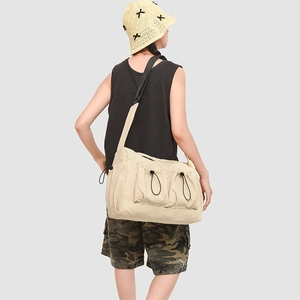 Detail of beige cargo crossbody bag with dual drawstring pockets and black adjustable strap