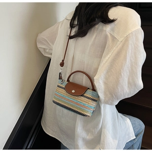 Detail of colorful woven straw texture with brown leather flap and metal buckle