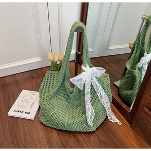 Détail d'un cabas vert au crochet avec un grand nœud en dentelle blanche dans un décor chaleureux