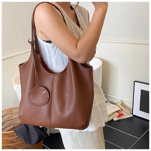 Détail du sac cabas en cuir marron à grain de litchi avec une petite pochette assortie