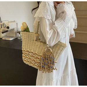 Close-up of woven straw tote bag with evil eye tassel and bohemian wave pattern
