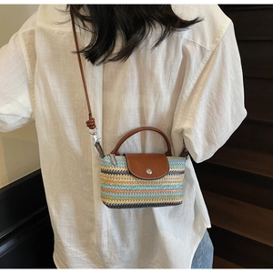 Detail of multi-color woven straw bag with brown leather flap and embossed fashion logo