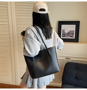 Detail of minimalist black tote bag with silver logo and vertical stitching