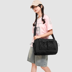 Detail of black nylon messenger bag featuring drawstring multi-pockets and wide strap
