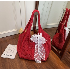 Détail macro du sac cabas en crochet rouge avec texture ajourée et nœud en dentelle