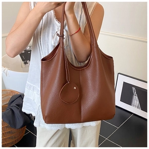 Détail d'un sac cabas marron foncé en cuir grainé avec de longues bandoulières