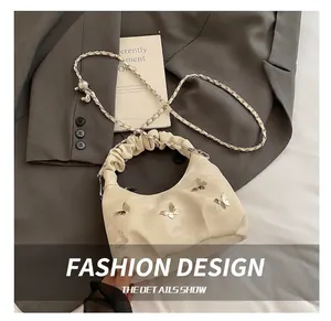 Détail du sac à main plissé blanc cassé avec papillons argentés et bandoulière chaîne