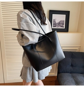 Detail of the large black minimalist tote bag with gold lettering shown on a female model