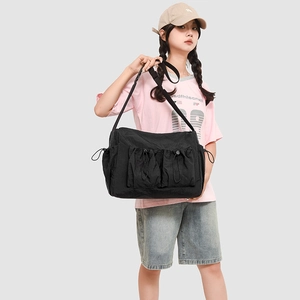 Detail of black nylon tote bag featuring two front drawstring utility pockets for commute