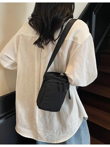 Minimalist black nylon mini drawstring bucket bag shown worn on a model's back