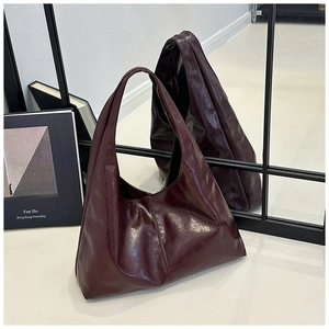 Nahaufnahme einer burgunderroten glänzenden Hobo-Tasche mit Vintage-Textur und großem Volumen