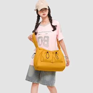 Detail of bright yellow crossbody bag with double front drawstring pockets and wide strap