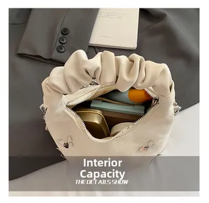 Capacité interne du sac plissé beige avec détail papillon argenté et rangement