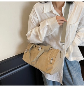 Detail of a khaki nylon travel bag with silver zippers and wide shoulder strap