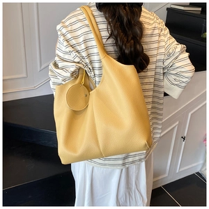 Vue détaillée d'un sac cabas jaune gingembre avec texture cuir et pochette ronde suspendue