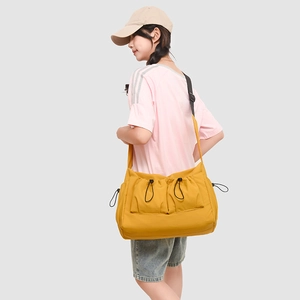 Detail of yellow nylon crossbody bag with dual drawstring pockets and black strap