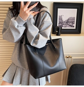 Detail of black matte leather tote bag with vertical stitching and fashion typography