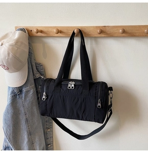 Detail of black nylon duffel bag featuring dual metal zippers and adjustable shoulder strap