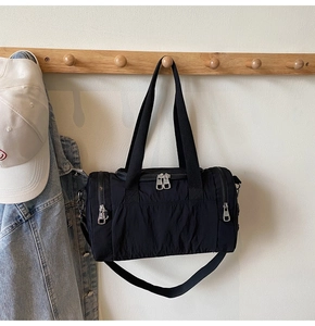 Detail of a black nylon duffel bag featuring double zippers and durable webbing handles