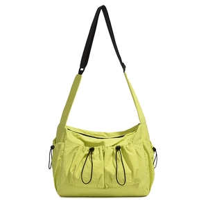 Detail of light green nylon tote bag featuring front drawstring pockets and sporty strap