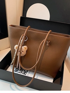 Brown lychee texture leather tote bag with cute bear charm on a stylish background