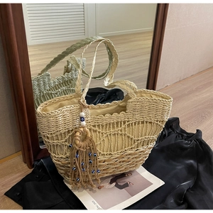 Detail of woven straw tote bag featuring wave pattern with evil eye tassel charm