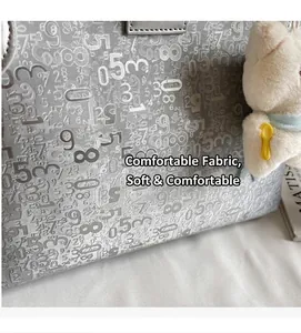 Close-up of grey tote bag with embossed numbers and a cute plush bear keychain