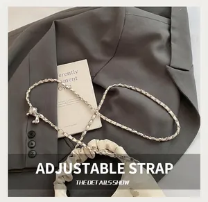 Détail de la bandoulière réglable avec boule en métal sur le sac plissé couleur crème