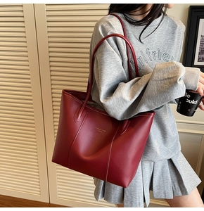 Side view of large deep red leather tote bag showing carrying capacity and shoulder drape