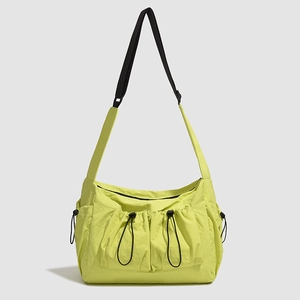 Detail of neon green nylon tote bag with drawstring pockets and wide shoulder strap