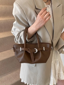 Sac seau vintage en cuir marron avec boucle lune en métal porté par un mannequin sur escalier