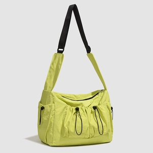 Detail of neon green nylon tote bag featuring adjustable drawstring pockets and textured fabric