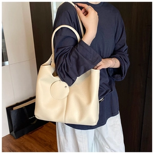 Détail du sac cabas en similicuir blanc crème avec texture grainée et pendentif rond