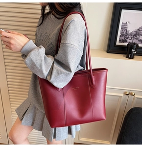 Detail of burgundy leather tote bag showing fine texture and sleek handle design