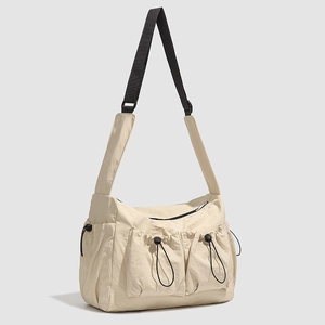 Detail of beige nylon tote bag featuring functional drawstring pockets and black strap