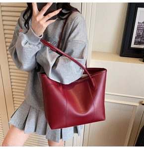 Side view of large red faux leather tote bag with gold lettering and vertical stitching