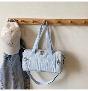 Light blue nylon duffel bag hanging with casual denim jacket and baseball cap