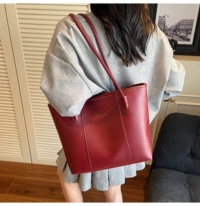 Detailed view of burgundy leather tote bag with gold lettering shown in lifestyle setting