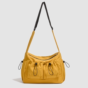 Detailed view of yellow nylon tote bag with dual front drawstring pockets and black strap