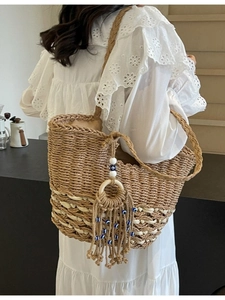 Handwoven straw tote bag with evil eye tassel charm and striped accents for summer beach