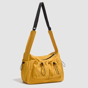 Detail view of large yellow nylon tote bag with drawstring pockets and black strap