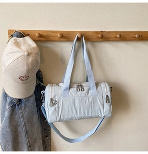 Close-up of light blue nylon travel bag hanging with double handles and hardware zippers