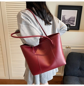 Detailed view of dark red tote bag in matte leather with gold lettering decoration