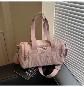 Detail of pink nylon duffel bag with textured fabric, zippers and adjustable strap
