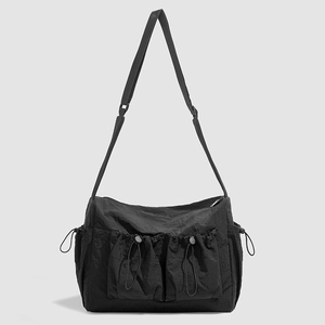 Detail of black nylon crossbody bag featuring drawstring pockets and functional utility style