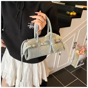 Detail of light blue denim Boston bag featuring a large bow and decorative metal buckles