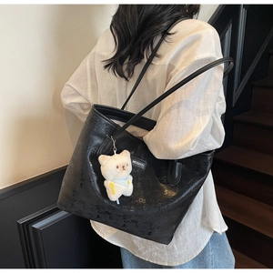 Close-up of black leather tote bag featuring retro numeric prints and a plush bear charm
