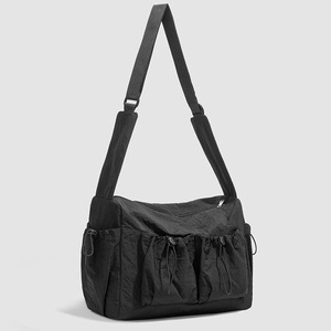 Close-up of black nylon crossbody bag featuring double drawstring pockets and padded strap